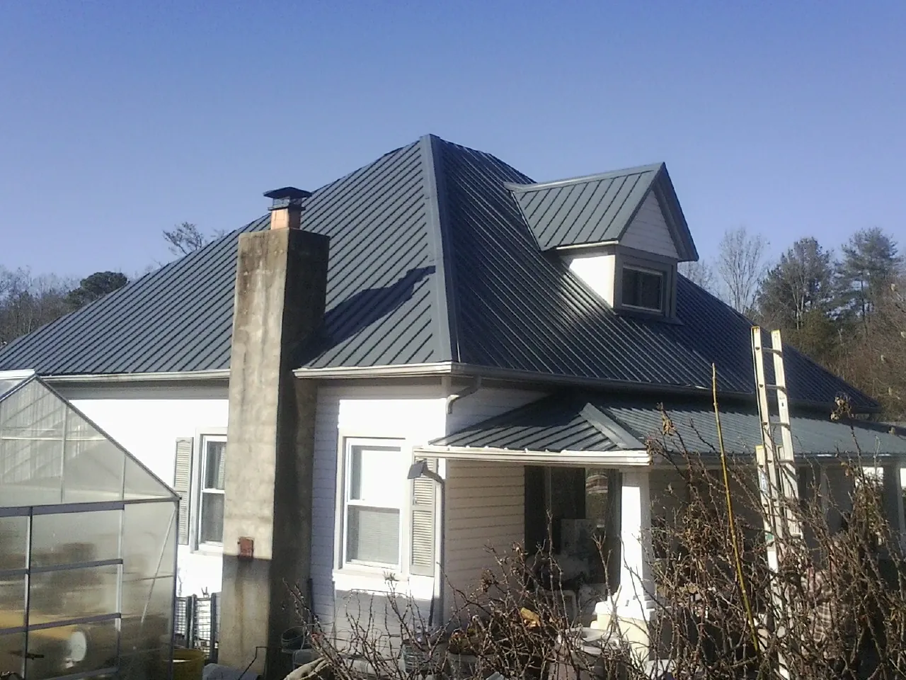 Dark blue standing seam metal roof on a white farmhouse with dormer — Slate & Tile Roof Repair by Roofing Brothers in Stuarts Draft
