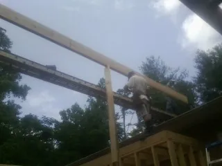 Carpenter setting a ridge beam over a new addition frame — Ice Dam Removal by Roofing Brothers in Stuarts Draft