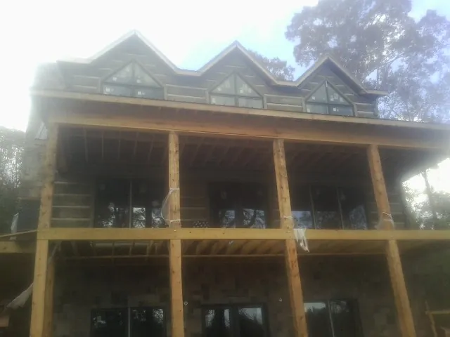 Dormers and porch framing on a large log home under construction — Roof Coating work by our crew in Stuarts Draft