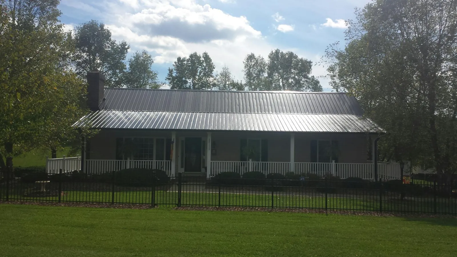 Gray metal roof on a brick ranch with a full width front porch — Gutter Guard Installation work by our crew in Stuarts Draft