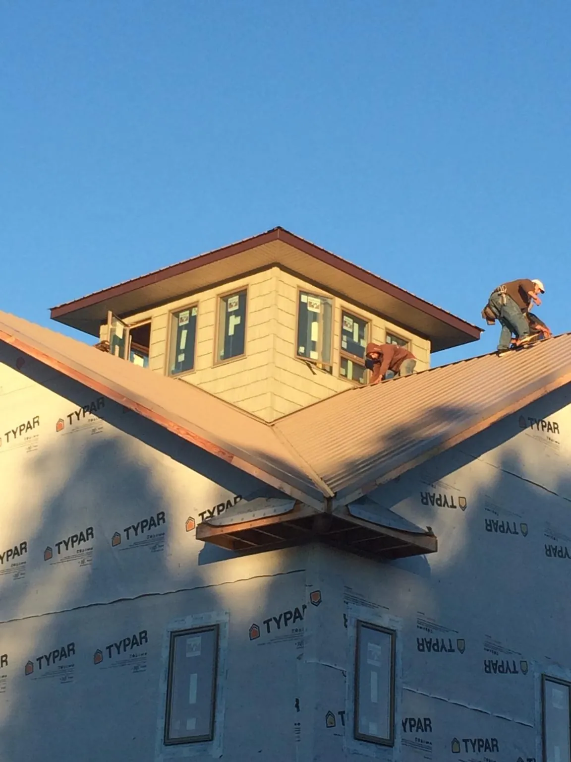 Roofers working around a rooftop cupola on a new metal roof at sunset — Roof Waterproofing in Stuarts Draft by Roofing Brothers